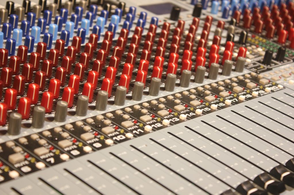 Close-up of audio mixing console with red and blue knobs, ideal for music production.