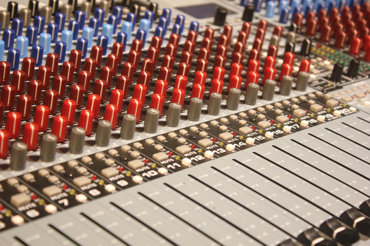 Close-up of audio mixing console with red and blue knobs, ideal for music production.